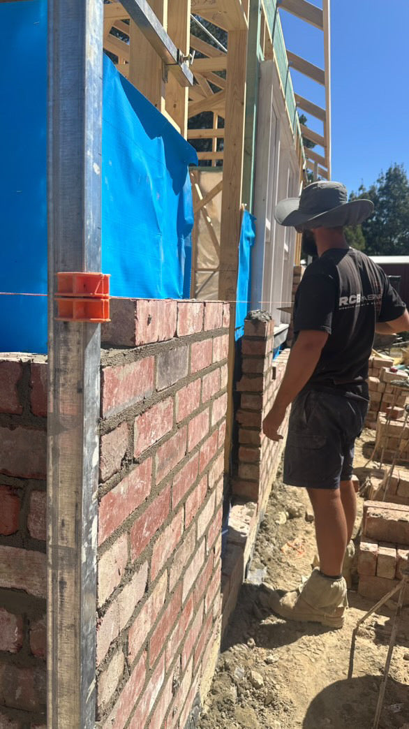Bricklayer using TradiesGear MAGSY magnetic corner blocks to run string line for even brickwork on a residential construction site