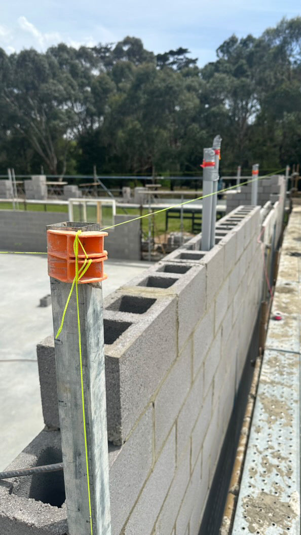 Accurate bricklaying tool for running long string lines on concrete block work at a commercial build site