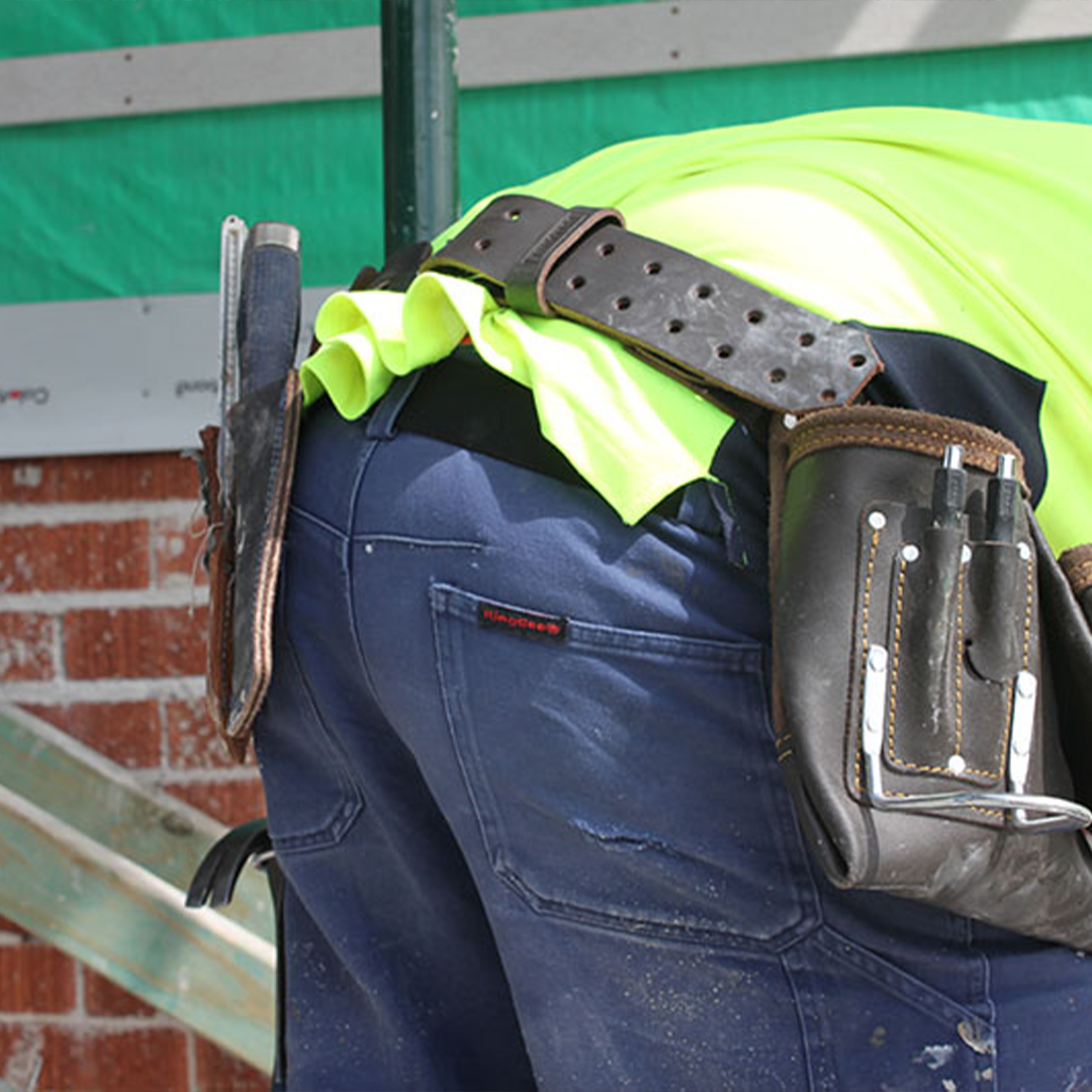 Tradies gear no buckle belt tradie wearing fluro shirt bent over belt holding pants firmly in place. no digging in. tool belt above tradies belt