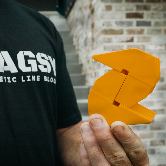 Tradesperson holding orange MAGSY magnetic line block tool for bricklaying